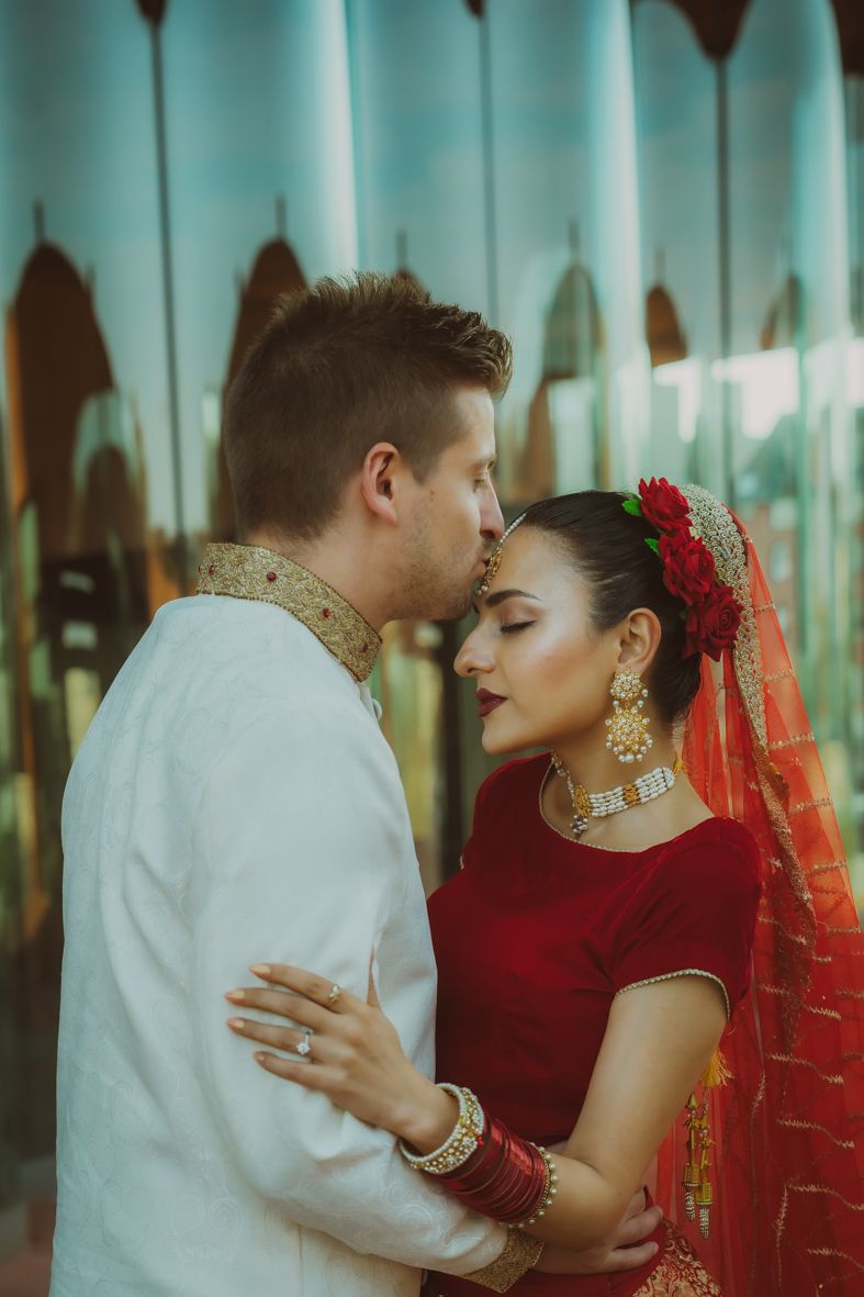 Intieme koppelportretten met bruid in traditionele rode Indiase kleding en bruidegom in wit