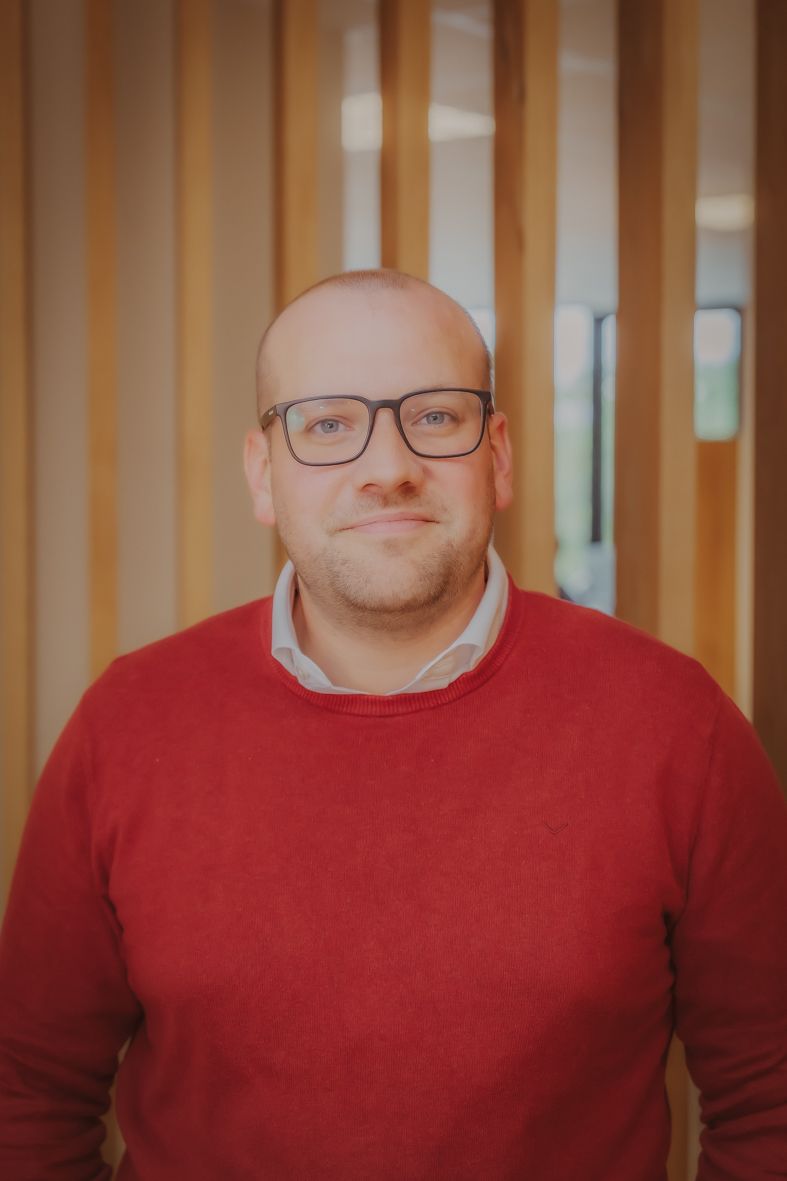 Persoon in rode trui en bril voor houten panelenwand