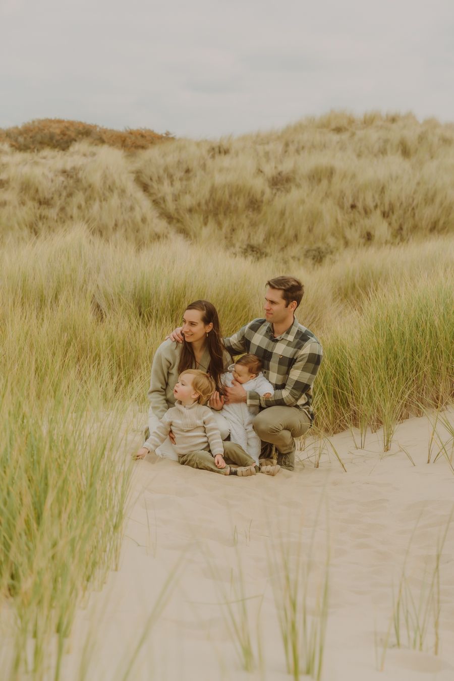 Gezin ontspant samen in de duinen in golden hour