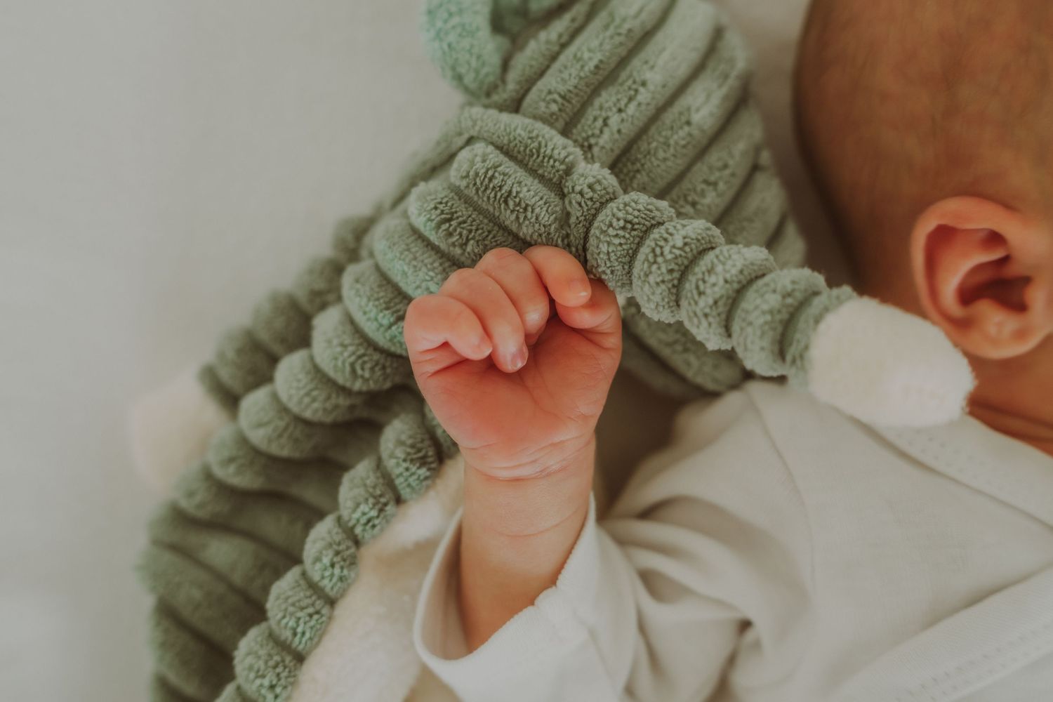 Baby in saliegroen truitje slaapt vredig