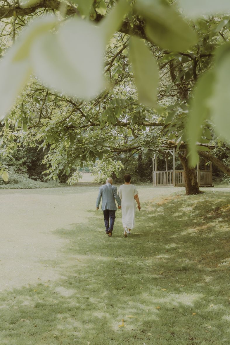 Koppel wandelt hand in hand door een zonnige tuin