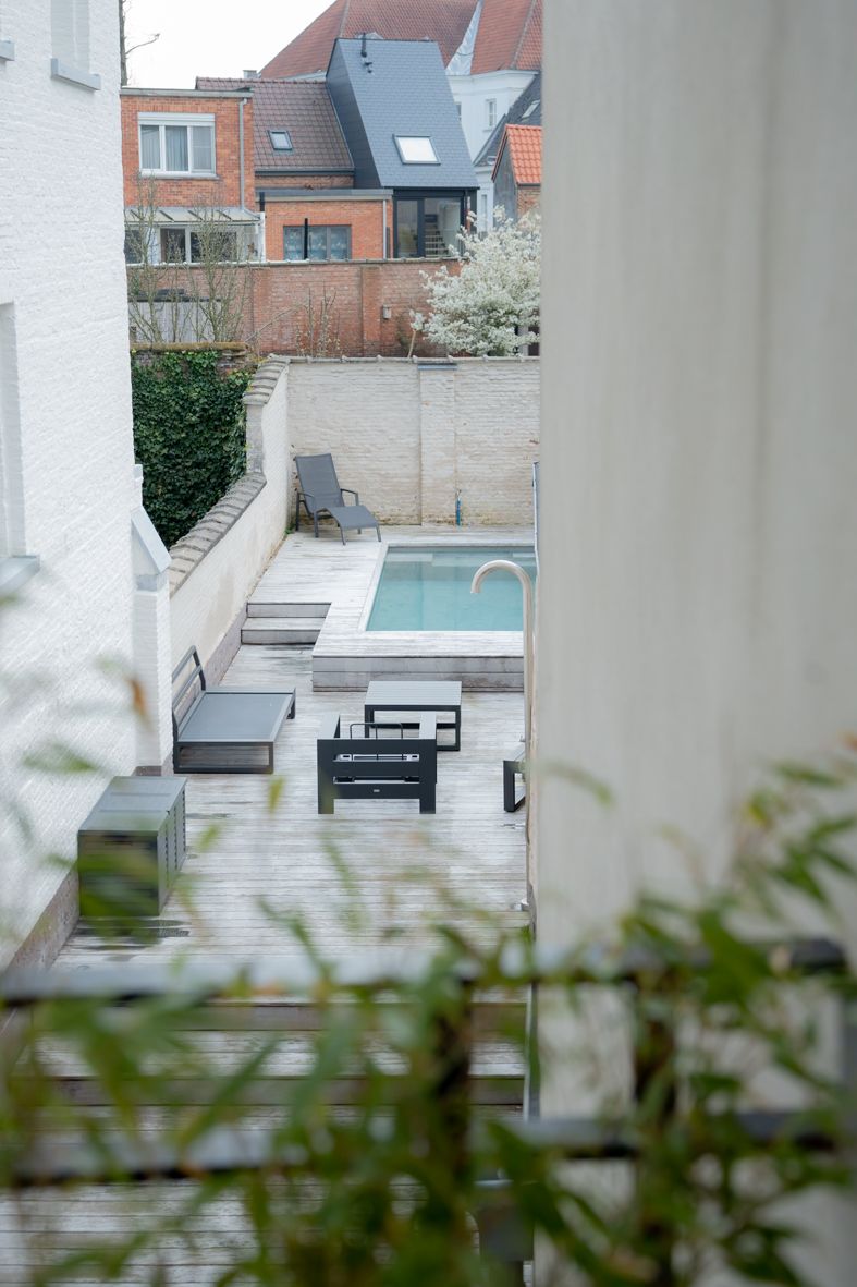 Zicht op moderne tuin met zwembad door witte architecturale kolommen