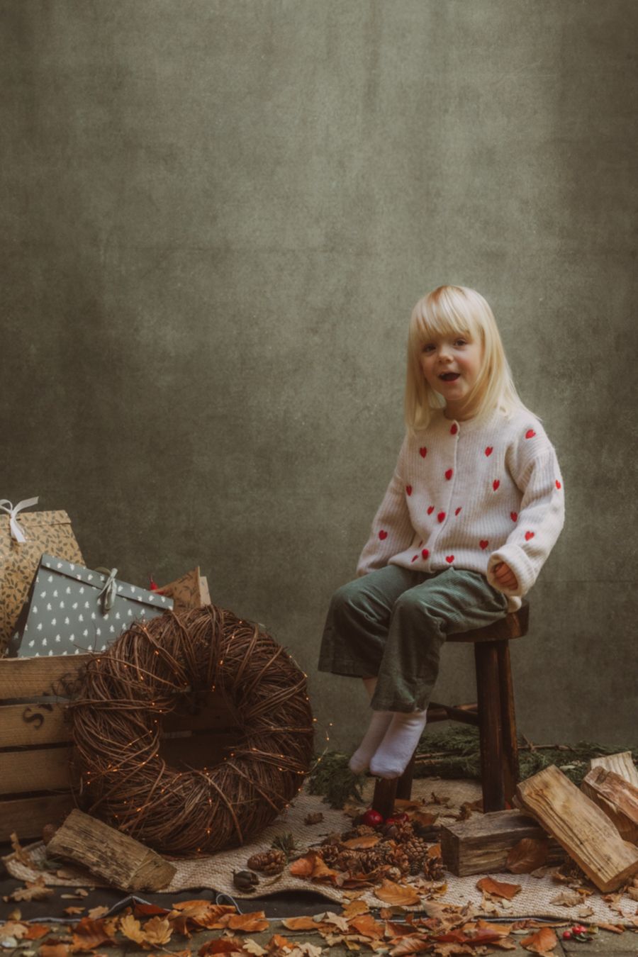 Kind bij rustieke krans en houtblokken in sfeervolle setting