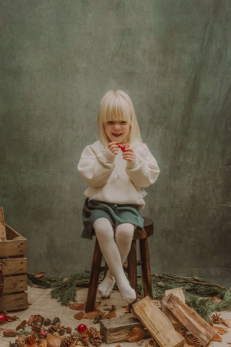 Kind in witte trui omringd door hout en aardbeien in sfeervolle setting