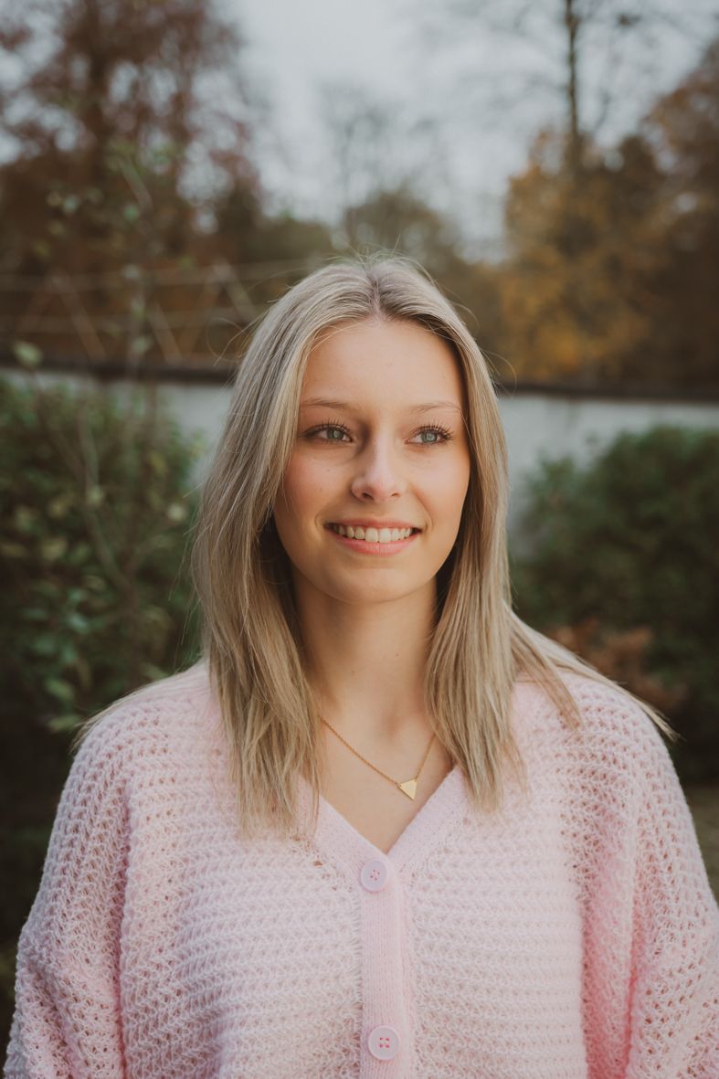 Persoon in zacht roze cardigan poseert buiten in herfst