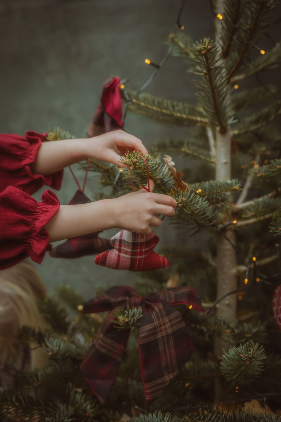 Handen in rode geruite mouwen versieren kerstboom
