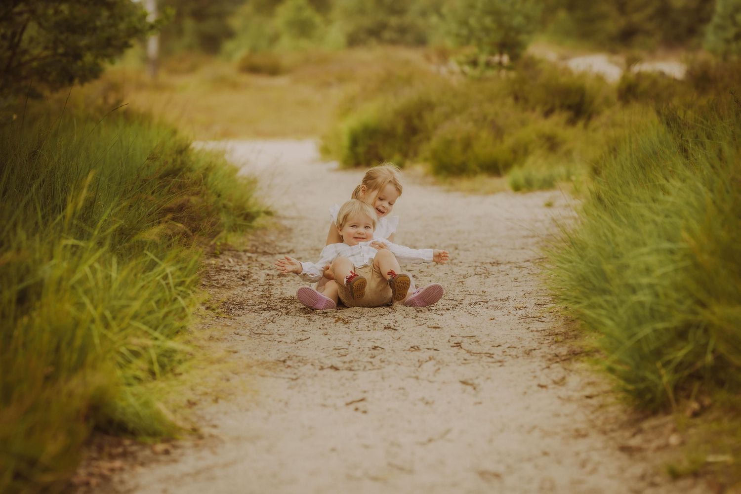 Kind speelt op een zandpad omgeven door hoog gras