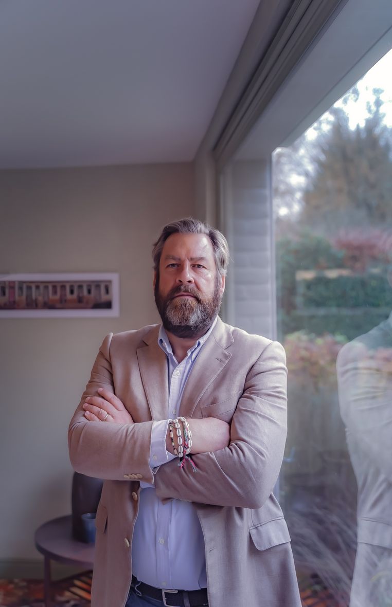 Professional in beige kostuum met armen gekruist in moderne kantooromgeving