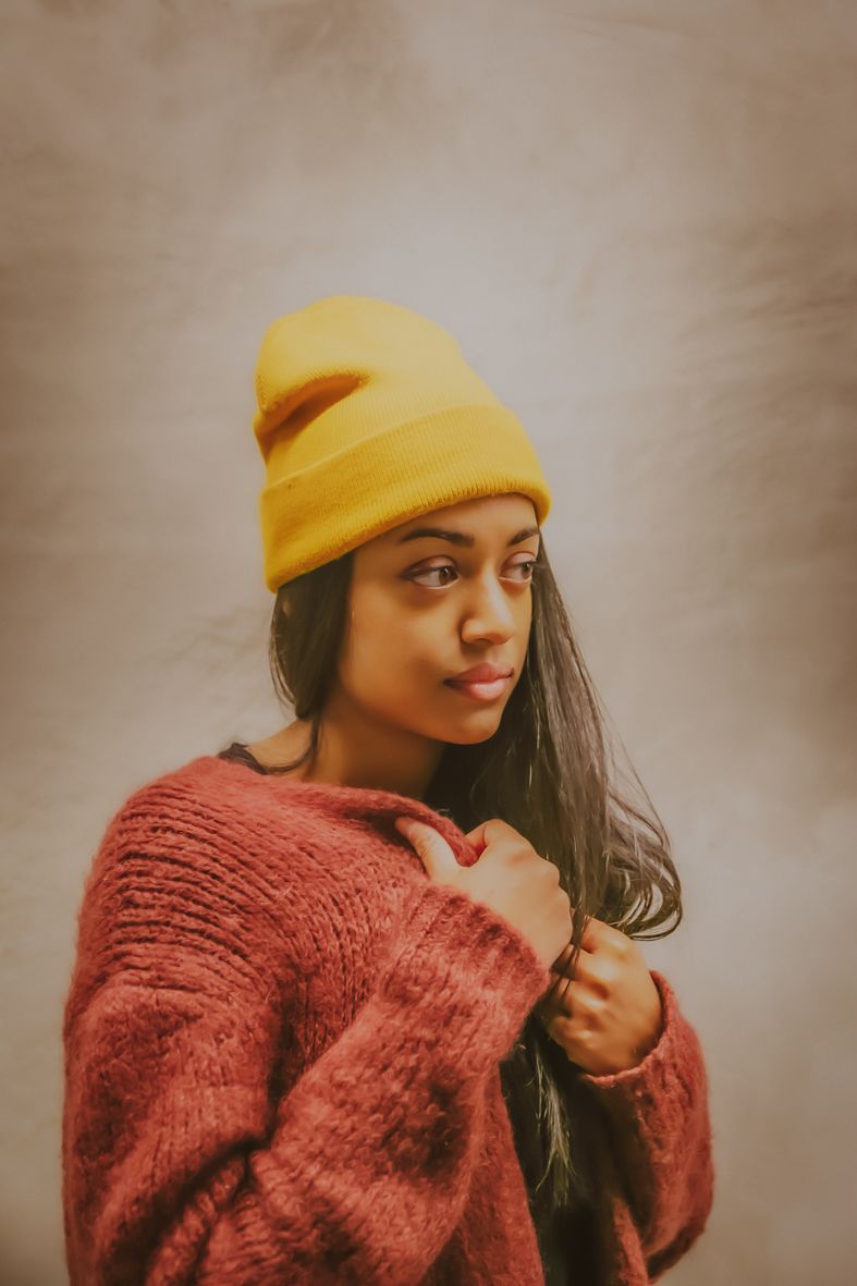 Persoon in gele muts en rode gebreide trui poseert in sfeervol portret