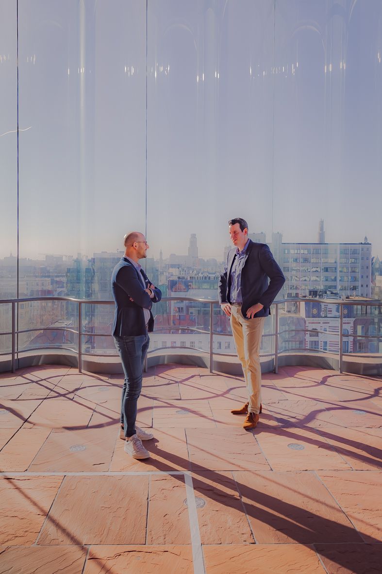 Twee mensen op zonnig dakterras met stedelijk landschap